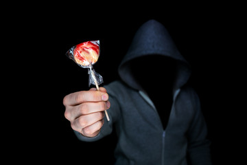 Unknown man holds out candy on a stick.