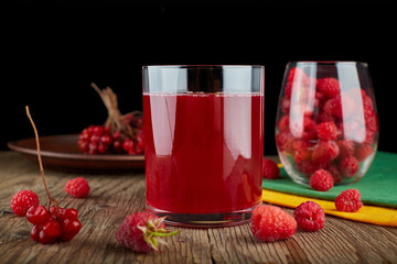 A glass of natural raspberry and cranberry juice on a wooden board