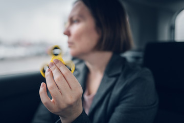 Businesswoman playing with fidget spinner in car