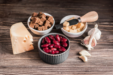 Healthy food: healthy food source against wooden background. Ingredients for cooking: red beans, hard cheese, crackers, brown bread, garlic.