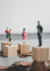 gender gap, difference income between man and woman, miniature man and woman stand on coin stacks