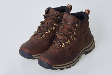 Brown trekking leather kids boots with shoelaces. Isolated on white 