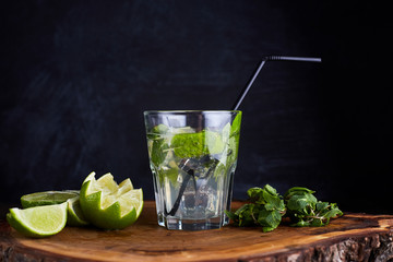 Fresh drink with lime, mint and ice on wooden table on dark background