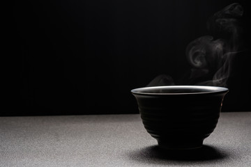 Soup hot in black bowl on wooden table,food steam and copy space ,selective focus.Fresh foods concept