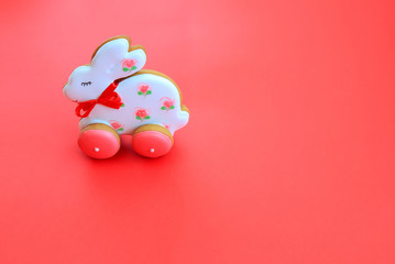 Easter holiday concept, handmade pink white gingerbread cookies in the form of a bunny on a red background. Gingerbread paschal rabbit