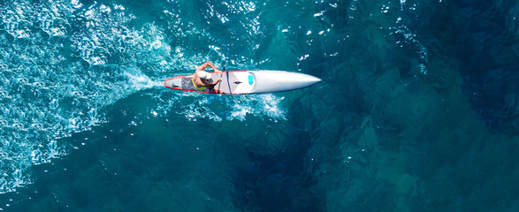 Aerial drone top down ultra wide photo of man practising in Stand Up Paddle or SUP board in...