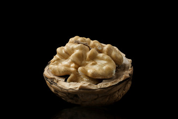 Macro photo of kernel walnut with reflection isolated on a black background.