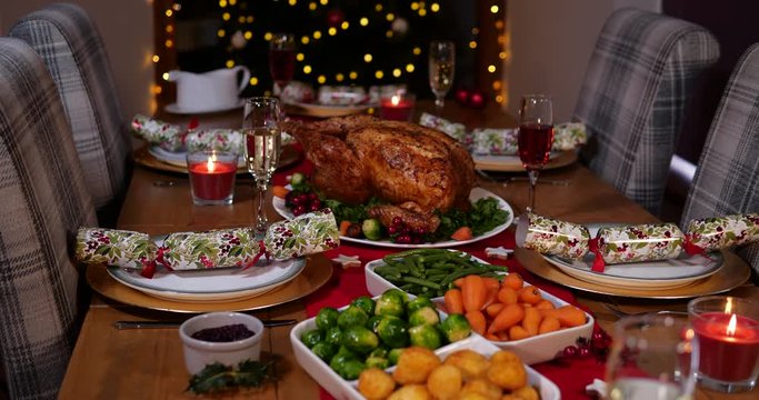 Christmas Dinner Table all set with Roast Turkey and delicious Vegetables. There is a Christmas tree behind and Christmas crackers.  Stock 4K Video Clip Footage