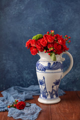 Coral Roses arranged in a Blue Vase with Blue Background on Wood Table