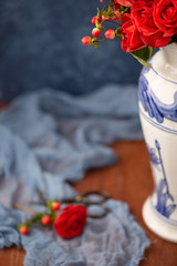 Coral Roses arranged in a Blue Vase with Blue Background on Wood Table