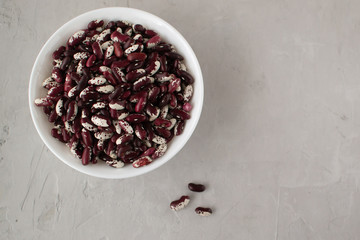 White and red beans in a white bowl on a gray background. Beans are a healthy, tasty and satisfying product. Clouse up. Top view.