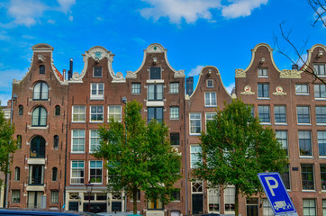 Fototapeta premium Amsterdam, Holland, August 2019. The typical and charming houses: they are a symbol of the city represented on a postcard. With brightly colored brick facades and distinctive roofs.