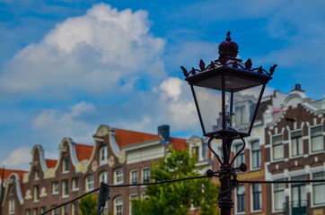 Fototapeta na wymiar Amsterdam, Holland, August 2019. The typical and charming houses: they are a symbol of the city represented on a postcard. With brightly colored brick facades and distinctive roofs. A lamppost frames.