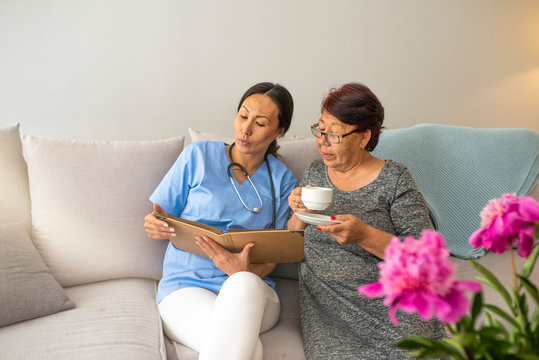 Shot of a young caregiver caring for her elderly patient in her home. Dementia and Occupational Therapy - Home caregiver and senior adult woman. Patient and caregiver spend time together