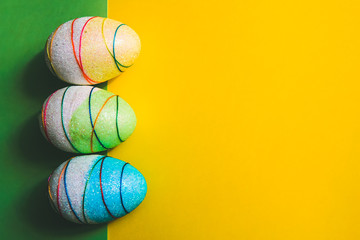 Colorful decorative Easter eggs on yellow and green background. Copy space.