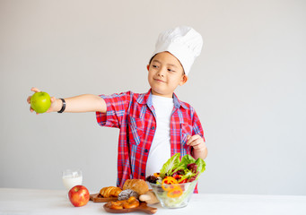 Asian red shirt little boy hold one apple and action with various types of fruits and vegetables on...