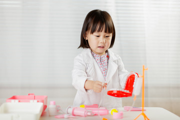 toddler girl pretend play  doctor role  at home against white background