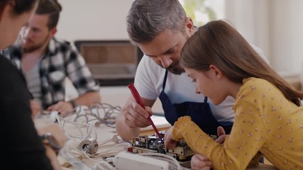 A group of people at repair cafe repairing household electrical devices.