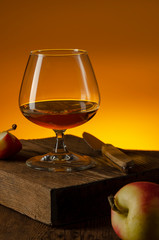 glass of Calvados Brandy and red apples on wooden table