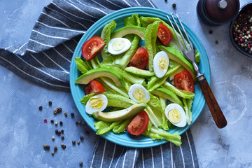 Vitamin salad with avocado, egg, cherry tomatoes on a concrete background.
