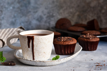 Christmas drink - hot chocolate with marshmallows and a cupcake on a concrete background.