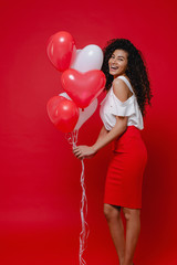 beautiful black woman smiling with heart shaped colorful balloons on red background