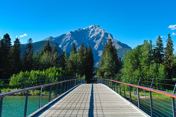 Fototapeta premium Bridge leading to Mr. Girouard in Banff, Alberta. Taken during a an early spring day with a beautiful blue sky.