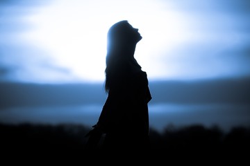 Youth woman soul at blue sun meditation awaiting future times. Silhouette in front of sunset or...