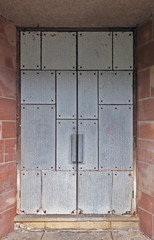 closed double doors covered in reinforced steel plates in an outdoor stone wall