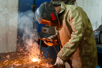 Worker in a welding mask for welding metal