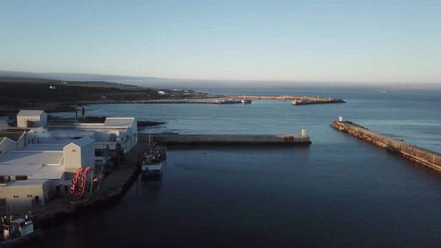 4K summer sunny morning aerial drone video of commercial harbour piers with vessels boats, fishing factory, town panorama, Indian Ocean coast town Gans Bay, Garden Route, Western Cape, South Africa