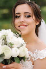 Close up portrait of gorgeous bride with bouquet. Happy woman smile