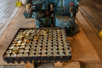 Many golden cans are coming from conveyor in old salmon cannery in Alaska. Fresh fish in the can. 