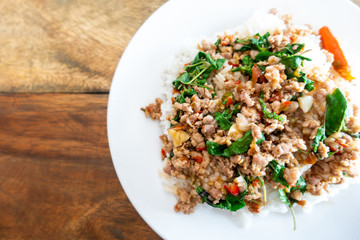 Rice topped with stir-fried pork and basil in a white dish. (Front focus)