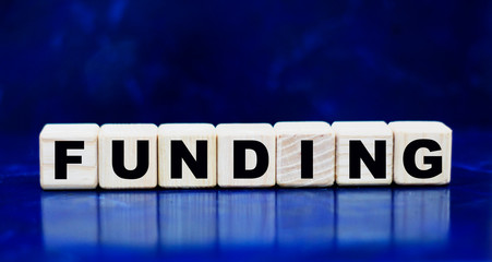 concept word funding on wooden cubes on a blue background