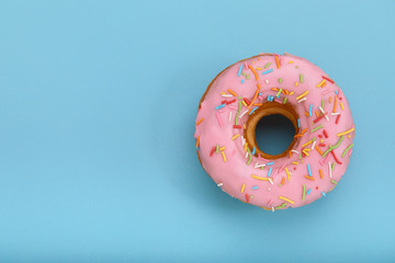 Pink donut on a blue background, top view, concept of desserts, pink color on blue. Copy space,...
