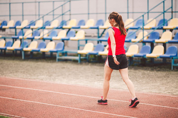 Woman Running At Stadium. Young woman running during on stadium track. Goal achievement concept. Fitness Jogging Workout on ballpark. Wellness theme. Sporty training cardio for weight loss success