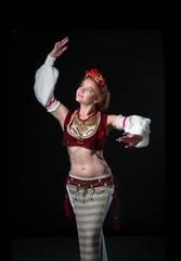 beautiful dancer in traditional folk costume in slavic stile with circlet of flowers, red vest,...