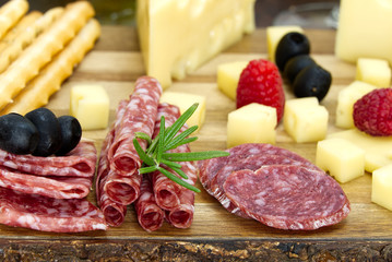 Meat and cheese plate antipasti snack with Prosciutto ham, Parmesan, Blue cheese, Cantaloupe melon and Olives on olive wood serving board on dark background