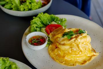 Flavored Fried Rice in an Omelet Wrapping with fish sauce and fresh chilli on side.