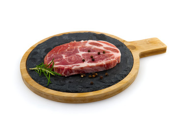 single raw pork slic on black stone plate, isolated on white.