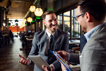 Two young businessmen talking in cafe at break