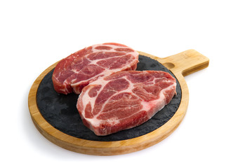 two raw pork slices on black stone plate, isolated on white.