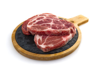 two raw pork slices on black stone plate, isolated on white.