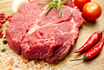 Raw beef steaks on wood board view from above. fresh steak with spices ready for cooking.