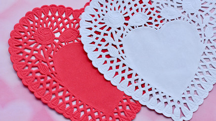 red and white paper lace doily close up on a pink and white background with copy space
