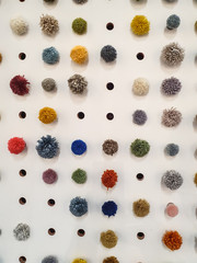Geometrical set of colorful pompons or bobs on a white peg board