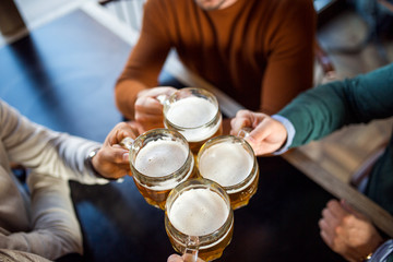 Four person holding beer glass and toasting
