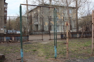 Fototapeta na wymiar old broken rusty exercise machines in the yard of a multi-storey building in the fall on a dirty Playground