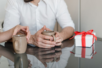 cups with drink for man and woman at table with gift at home